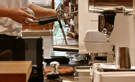 Barista preparing espresso with a coffee machine in a modern setup.