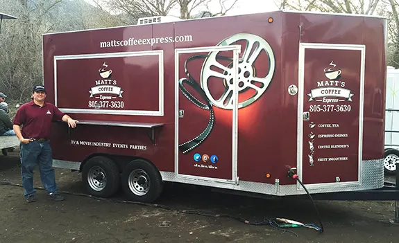 Burgundy mobile coffee truck with film reel graphic and contact information.